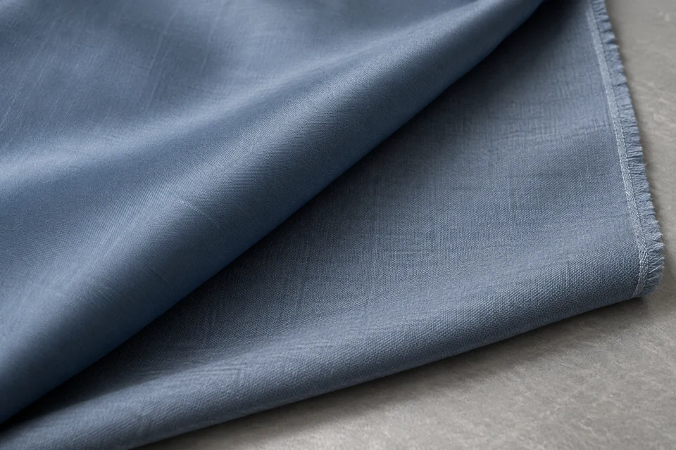 Close-up of folded slate-blue woven fabric showing contrasting face and reverse textures