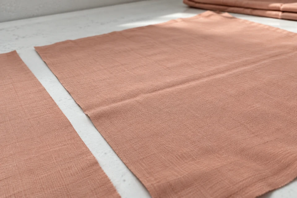 Pale terracotta fabric opened on a white inspection surface with a visible former fold line